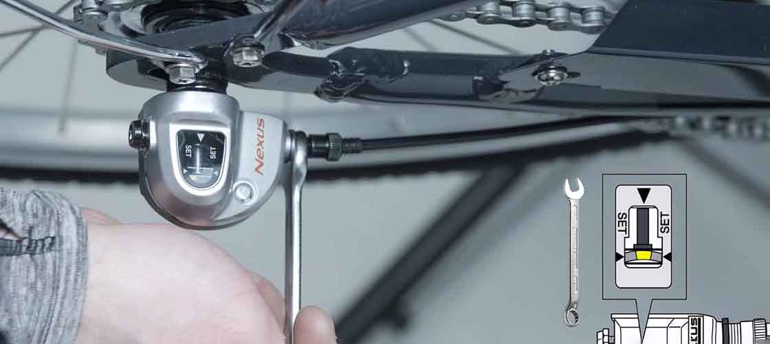 Close-up of a hand adjusting the gears with a Nexus brand on a bicycle.