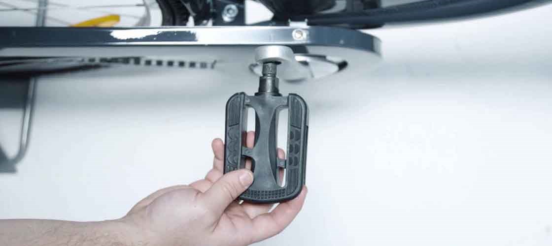 Close-up of a hand adjusting the pedal on a bicycle.