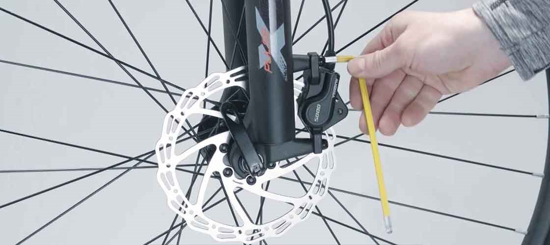 Närbild på en hand som justerar en cykels hydrauliska skivbromsar.