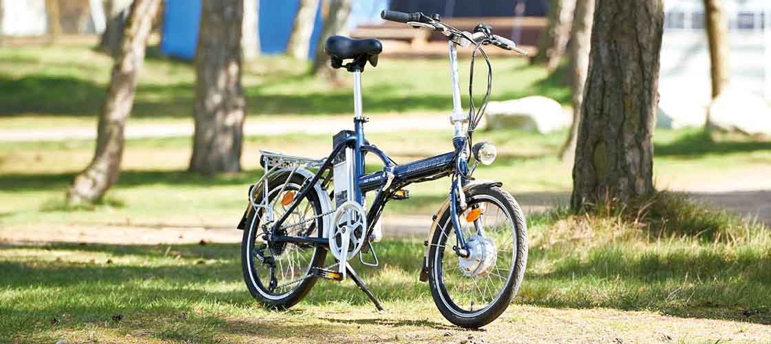 A folding bicycle parked in a sunny park.