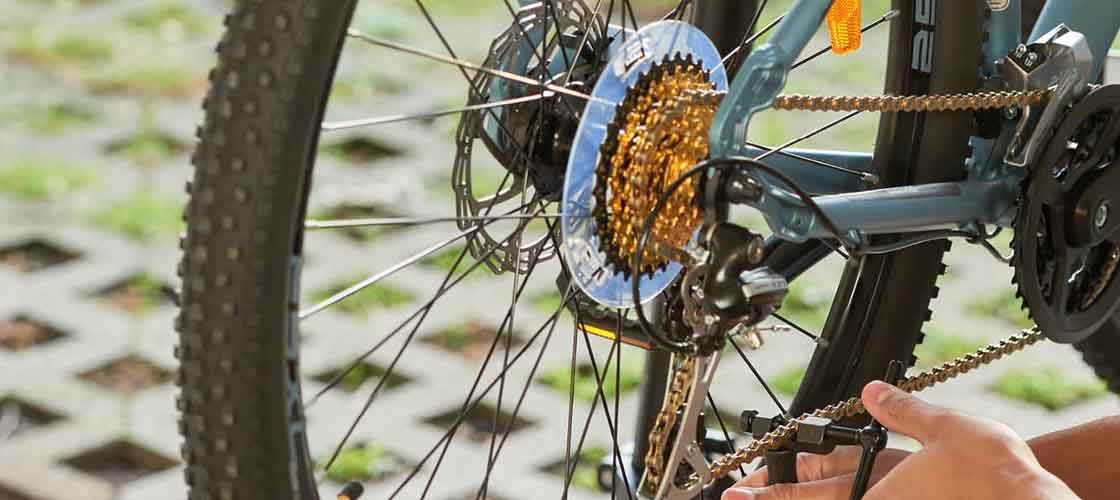 Close-up of a hand adjusting a bicycle chain in an outdoor environment.